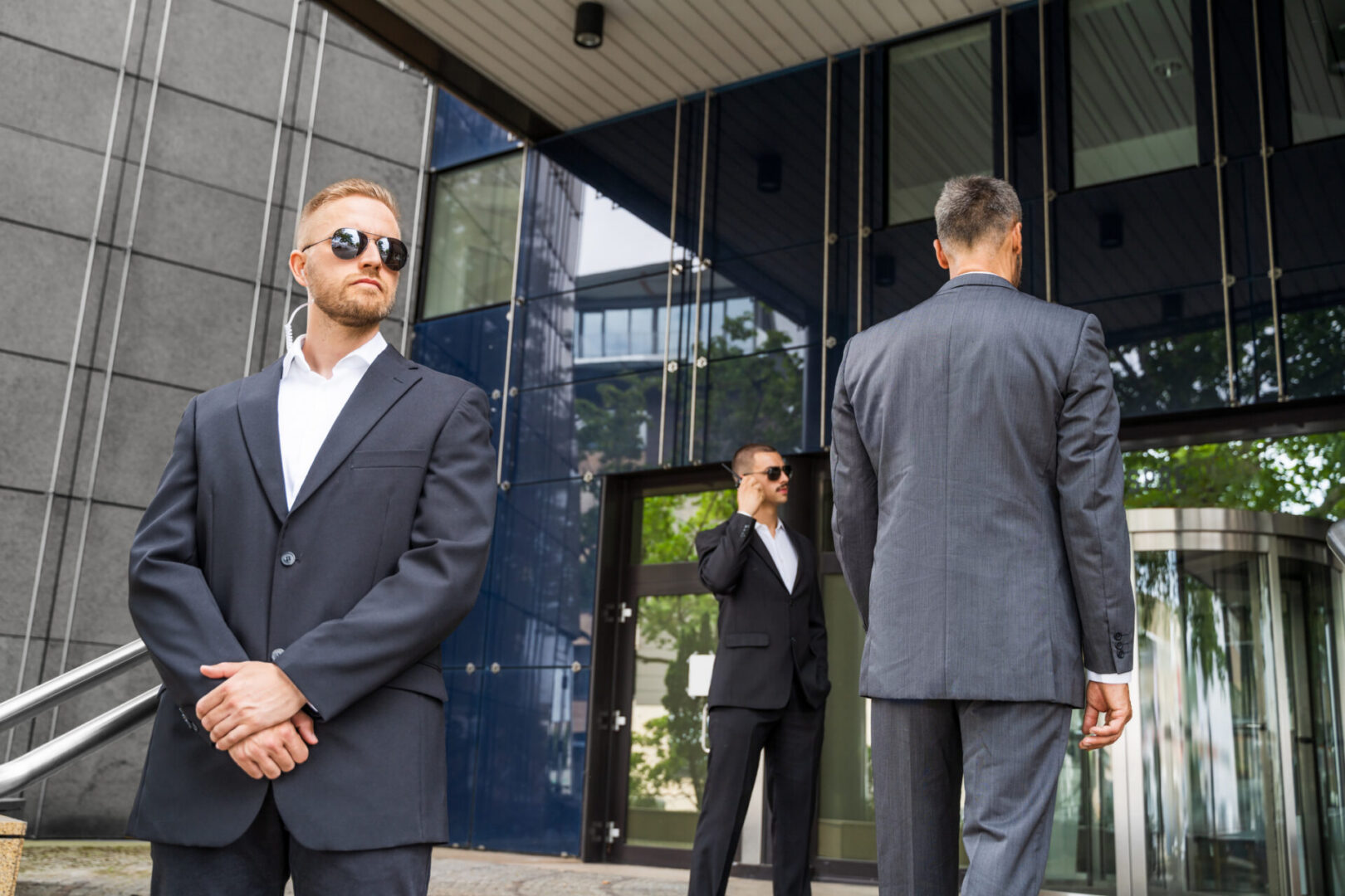 Three men in suits, building entrance