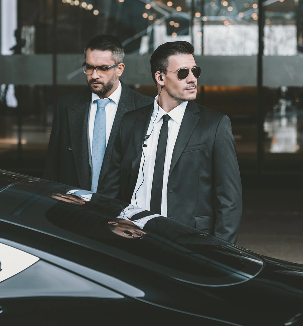Two security guards beside a car