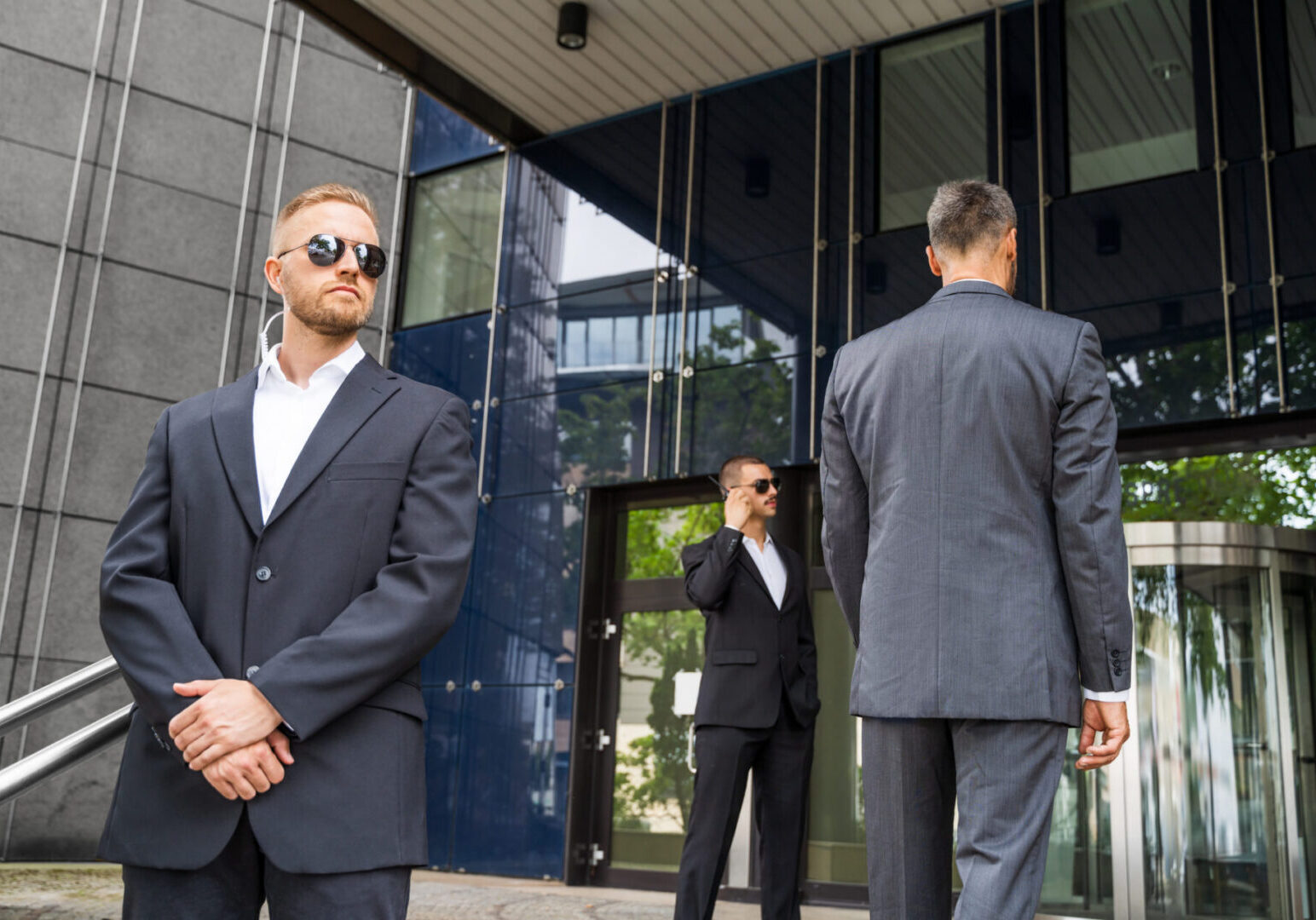 Three men in suits, building entrance